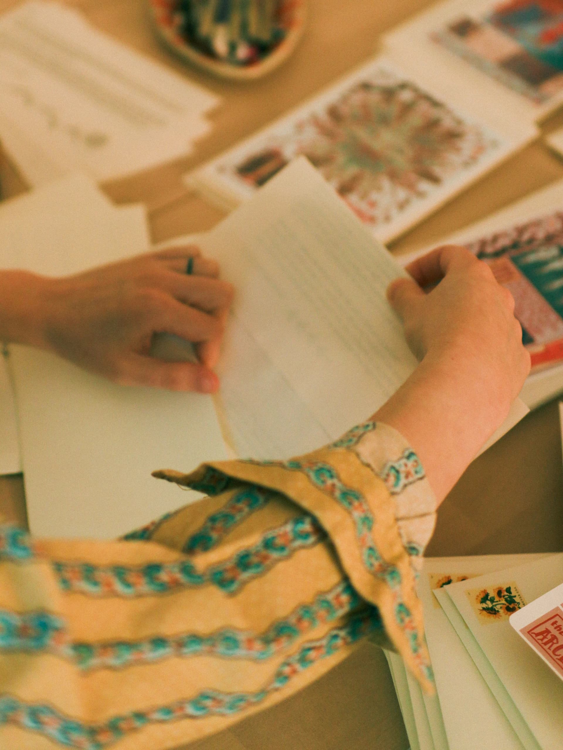 Artist’s hands preparing prints and stamped envelopes on a wooden desk